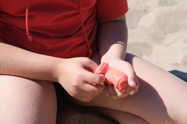 Jeune fille tenant une bave rouge vif dans ses mains. Éducation, créativité, concept d'enfance. Mise au point sélective.