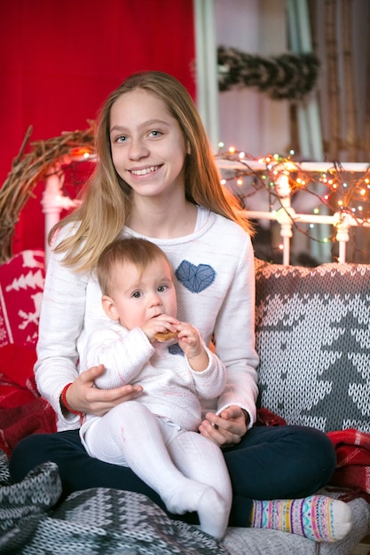 Jeune fille tenant un bébé dans un fond décoré de Noël