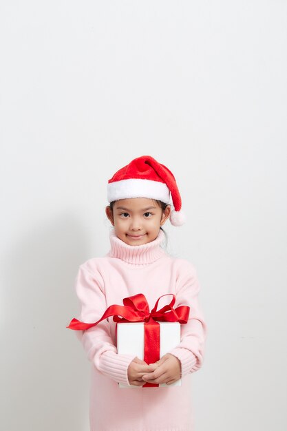 Jeune fille tenant une boîte-cadeau en pull et bonnet de Noel