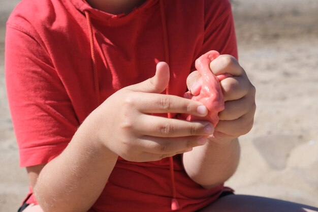 Jeune fille tenant une boue rouge vif dans ses mains concept d'enfance créativité éducation sélective