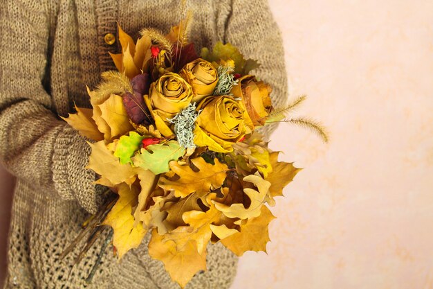 Jeune fille tenant un bouquet d'automne de feuilles sèches jaunes.