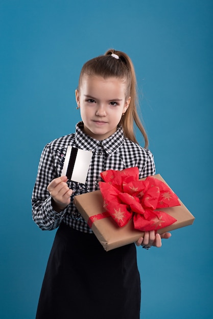 Jeune fille tenant un cadeau avec et une carte de crédit et souriant