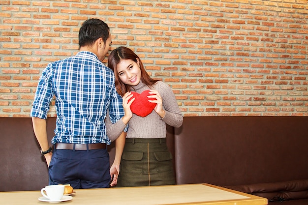 Jeune fille tenant un coeur rouge et son petit ami au restaurant