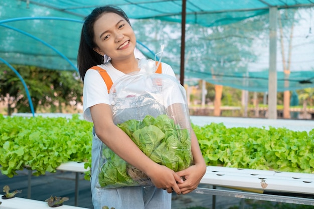 Jeune fille tenant un grand sac de légumes à la ferme hydroponique