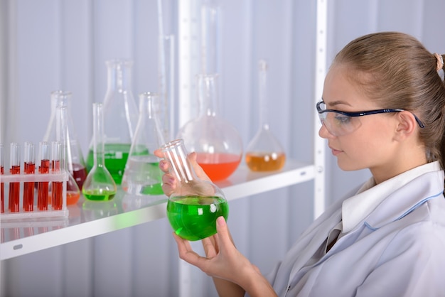 Jeune fille tenant un liquide vert dans les mains en laboratoire.