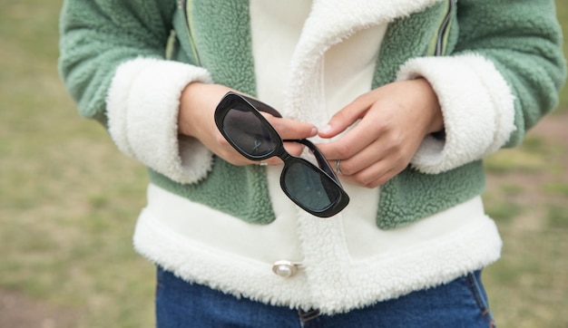 Une jeune fille tenant des lunettes de soleil à l'extérieur