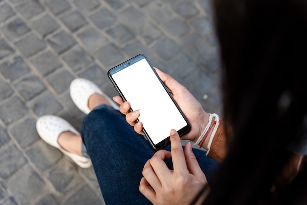 Jeune fille tenant une nouvelle technologie de téléphone dans la ville.