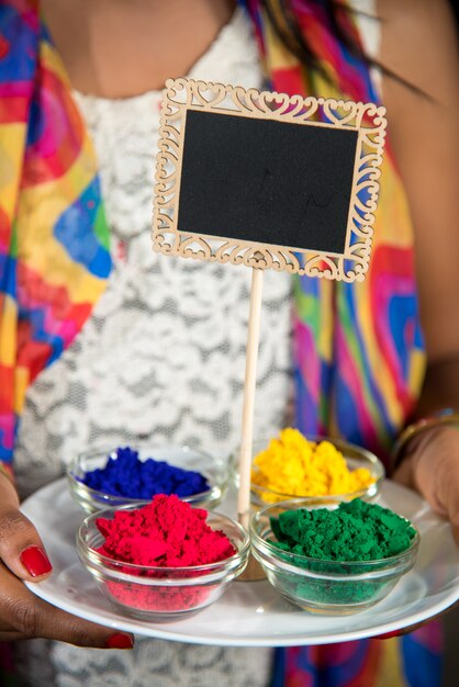 Jeune fille tenant une petite planche et une couleur poudrée à l'occasion du festival Holi.