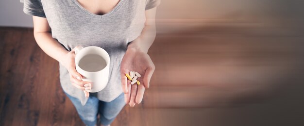 Jeune fille tenant des pilules et une tasse