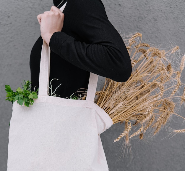 Jeune fille tenant un sac en tissu avec des épis de blé