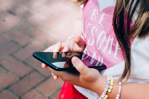 Jeune fille tenant un smartphone en photo ou en jouant