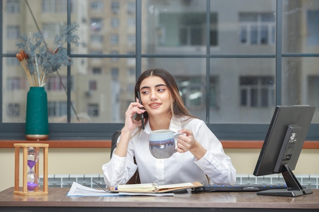 Jeune fille tenant une tasse de thé et parlant au téléphone