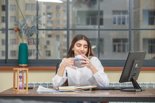 Une jeune fille tenant une tasse de thé et souriant Photo de haute qualité