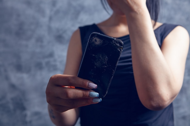 Jeune fille tenant un téléphone cassé