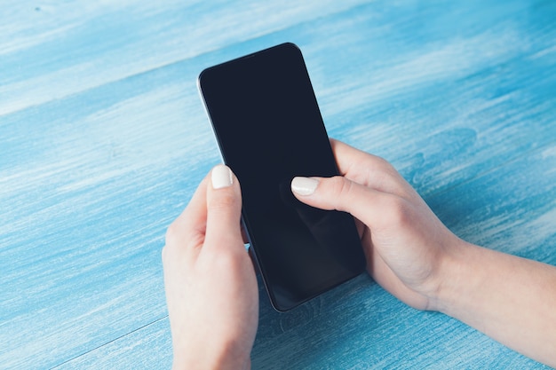 Jeune fille tenant un téléphone sur une table bleue