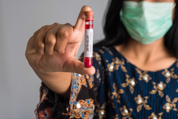 Jeune fille tenant un tube à essai avec un échantillon de sang pour le coronavirus ou l'analyse 2019-nCoV.