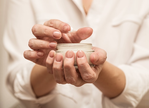 Une jeune fille tient un pot de crème dans ses mains