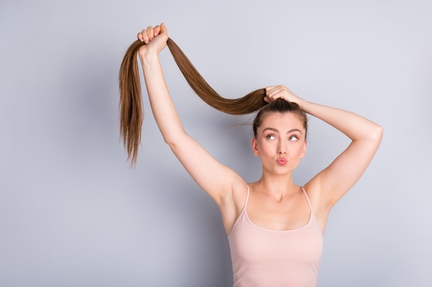 la jeune fille tient ses cheveux en queue de cheval avec ses mains