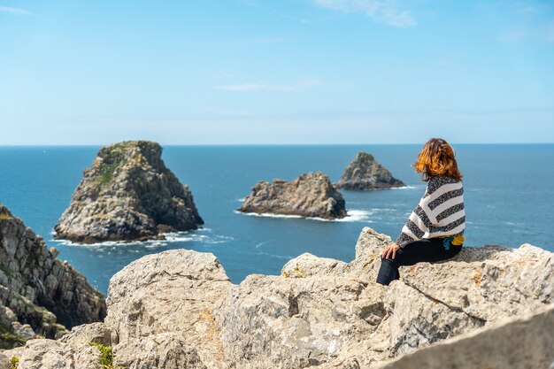 Une jeune fille touristique regardant la mer à Pen Hir Point sur la presqu'île de Crozon en Bretagne française, les trois célèbres îlots, France