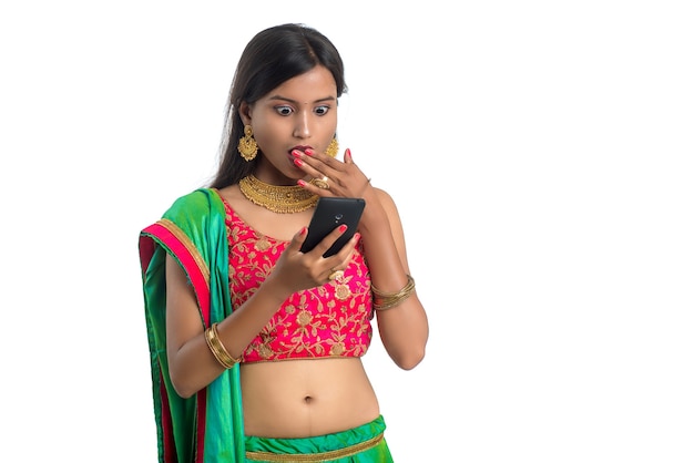 Jeune fille traditionnelle indienne à l'aide d'un téléphone mobile ou d'un smartphone isolé