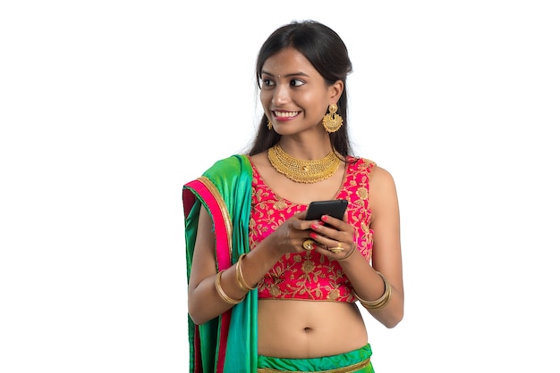 Jeune fille traditionnelle indienne à l'aide d'un téléphone mobile ou d'un smartphone isolé