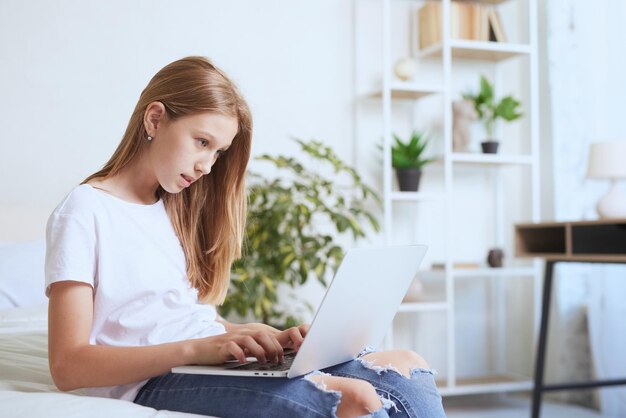 Jeune fille travaillant à la maison sur une formation en ligne pour ordinateur portable