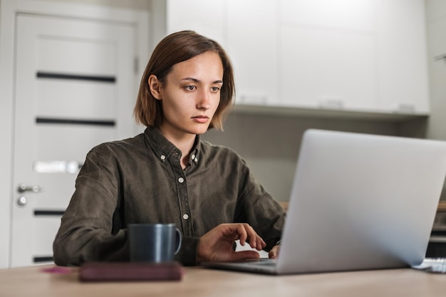 Jeune fille travaillant à l'ordinateur portable alors qu'elle était assise à la table