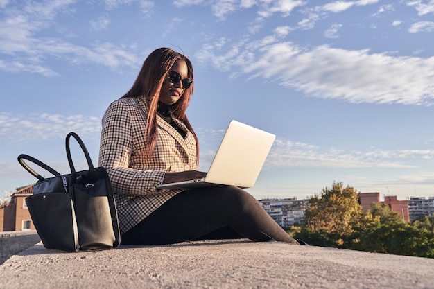 Jeune fille travaillant sur un ordinateur portable au coucher du soleil ou au lever du soleil le jour ouvrable