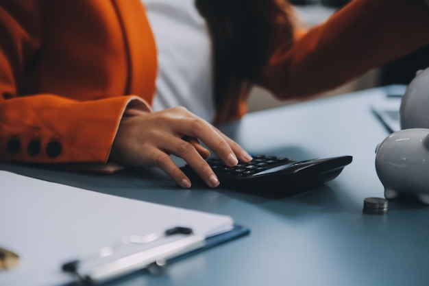 Une jeune fille travaille sur un ordinateur portable écrit un plan de développement d'entreprise dans un bloc-notes développe une stratégie et fait des calculs des fonds gagnés Une femme met ses économies dans une tirelire