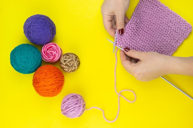 La jeune fille tricote un foulard pour enfants sur fond jaune