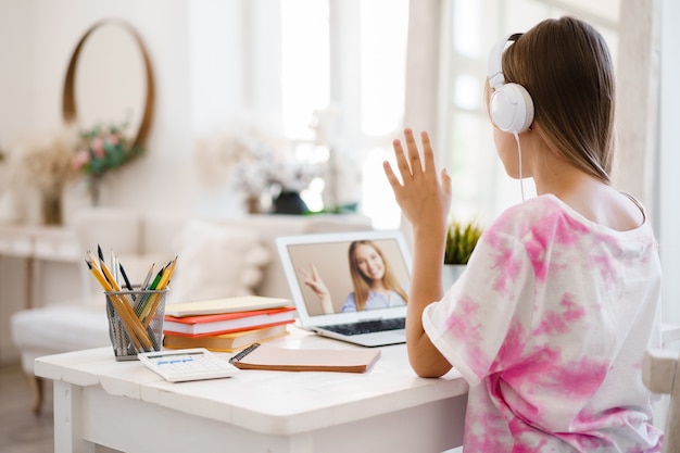 Jeune fille utilisant un ordinateur portable pour faire ses devoirs à la maison