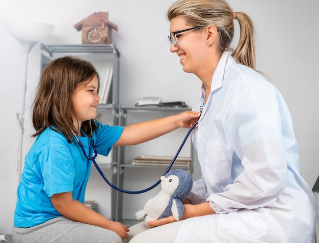 La jeune fille utilise un stéthoscope écoute le médecin Enfant au cabinet du médecin