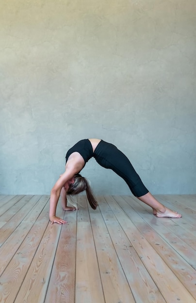 Une jeune fille en vêtements de sport fait du yoga fitness à la maison des sports à la maison qui s'étend