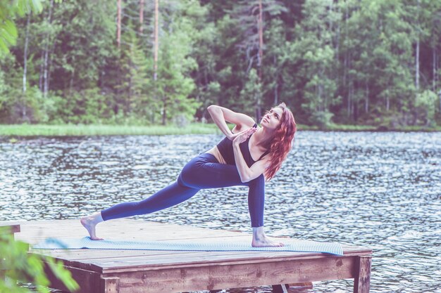 Jeune fille yogi pratiquant le yoga Parsvakonasana angle latéral pose sur le lac Concept de vie saine et d'équilibre naturel
