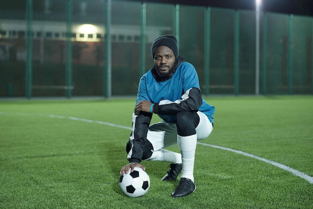 Jeune footballeur africain avec ballon de football assis sur des squats