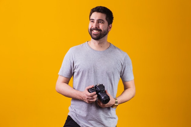 Jeune garçon avec un appareil photo à la main. Beau photographe sur fond jaune