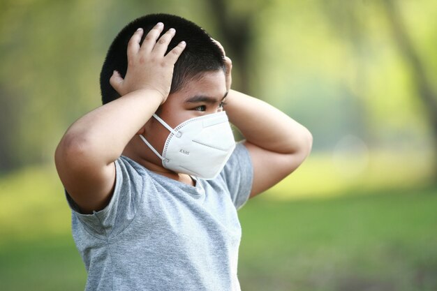 Un jeune garçon asiatique de 7 ans porte un masque pour se protéger de la poussière PM 2,5 et des germes