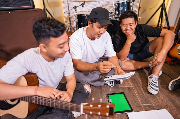 Un jeune garçon asiatique écrit une notation de chanson pendant que son ami joue de la guitare