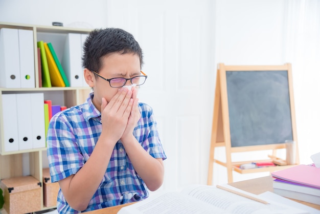 Jeune garçon asiatique essuie son nez par du papier de soie dans sa classe à l'école