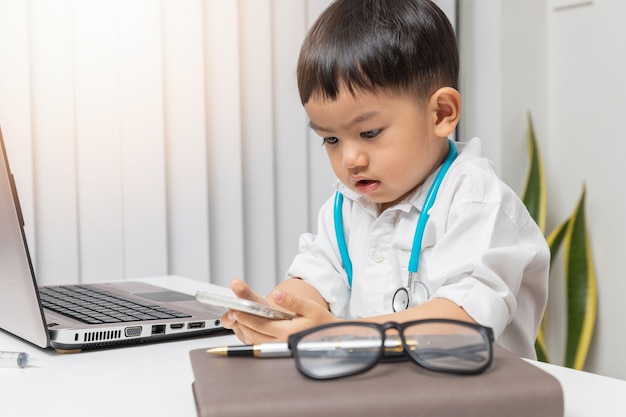 Jeune garçon asiatique jouant au médecin et écrivant sur le tableau de diagnostic.