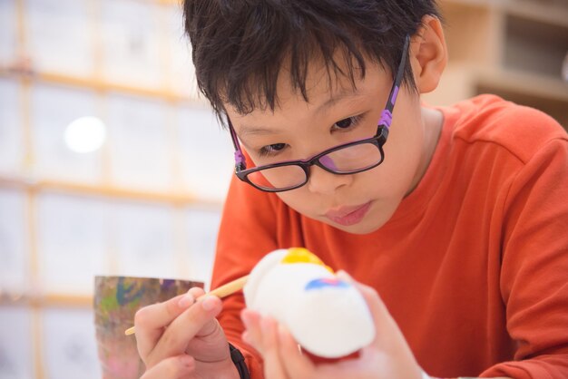 Jeune garçon asiatique peinture artisanale par couleur dans la salle de classe