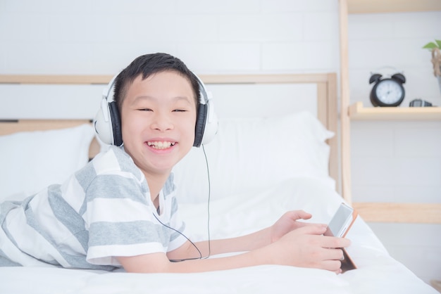 Jeune garçon asiatique portant un casque tout en utilisant un ordinateur tablette dans la chambre