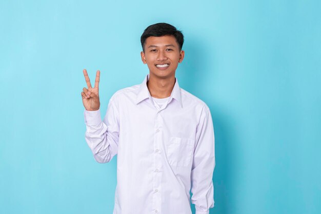 Photo jeune garçon asiatique portant un sourire heureux à manches longues montrant des doigts faisant deux signes isolés sur bleu