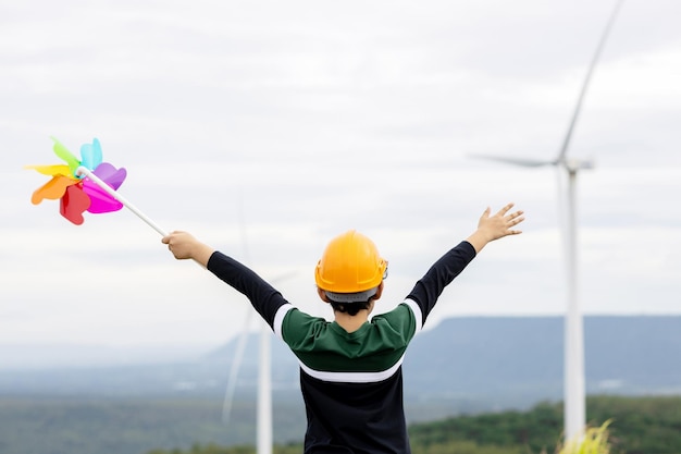 Jeune garçon asiatique progressiste jouant avec un jouet moulin à vent à la ferme éolienne