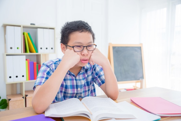 Jeune garçon asiatique se sentir fatigué et somnolent de lire un livre