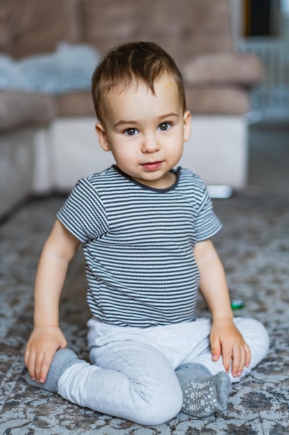 Un jeune garçon assis sur le sol dans une pièce confortable Un petit garçon assise sur le sol d'une pièce