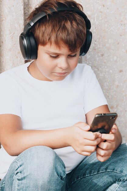 Jeune garçon au casque avec smartphone écoute de la musique dans le parc d'été. photo de haute qualité