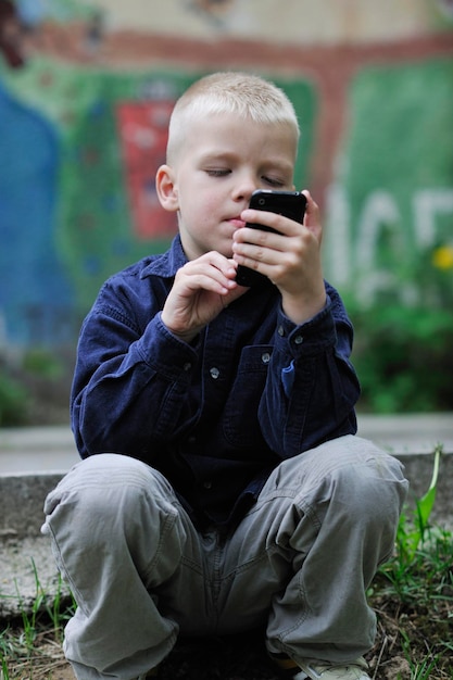 jeune garçon blond jouant à des jeux vidéo en plein air dans le parc