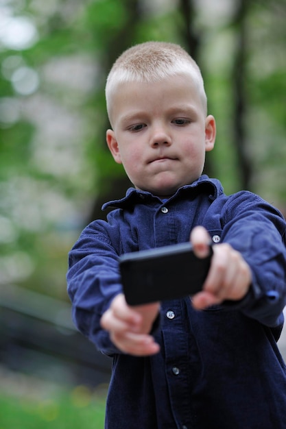 jeune garçon blond jouant à des jeux vidéo en plein air dans le parc