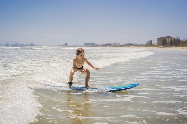 Jeune garçon en bonne santé apprenant à surfer dans la mer ou l'océan